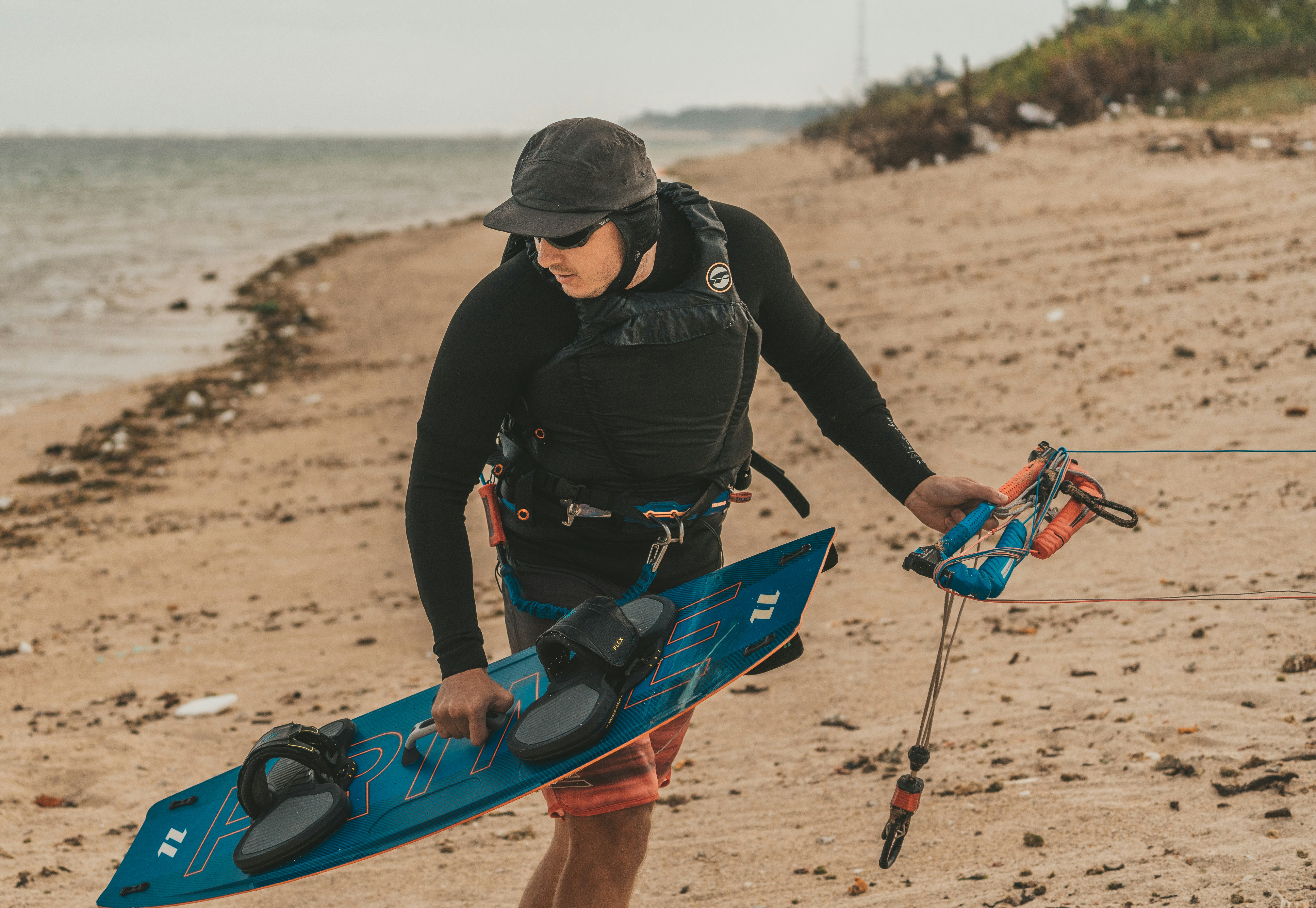a man holding a blue surfboard on top of a sandy beach