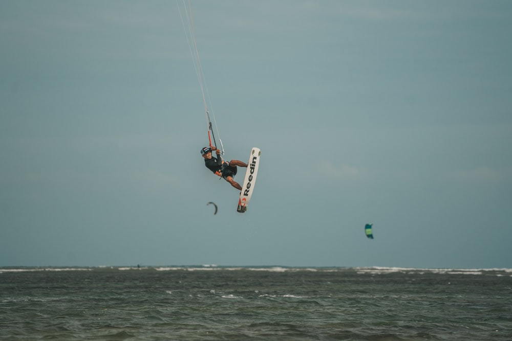 a man is parasailing over the ocean on a clear day