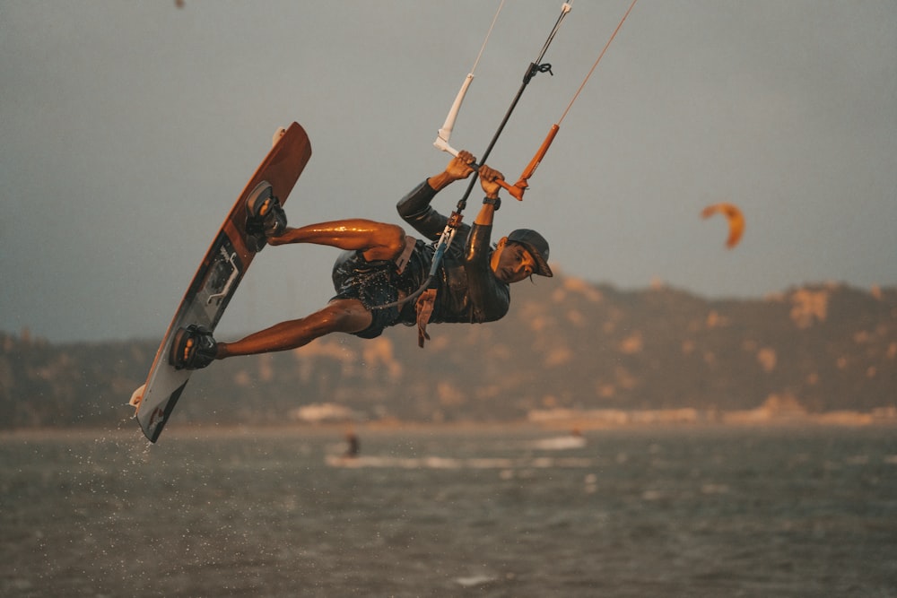 Un hombre montando un kiteboard mientras se aferra a un mango