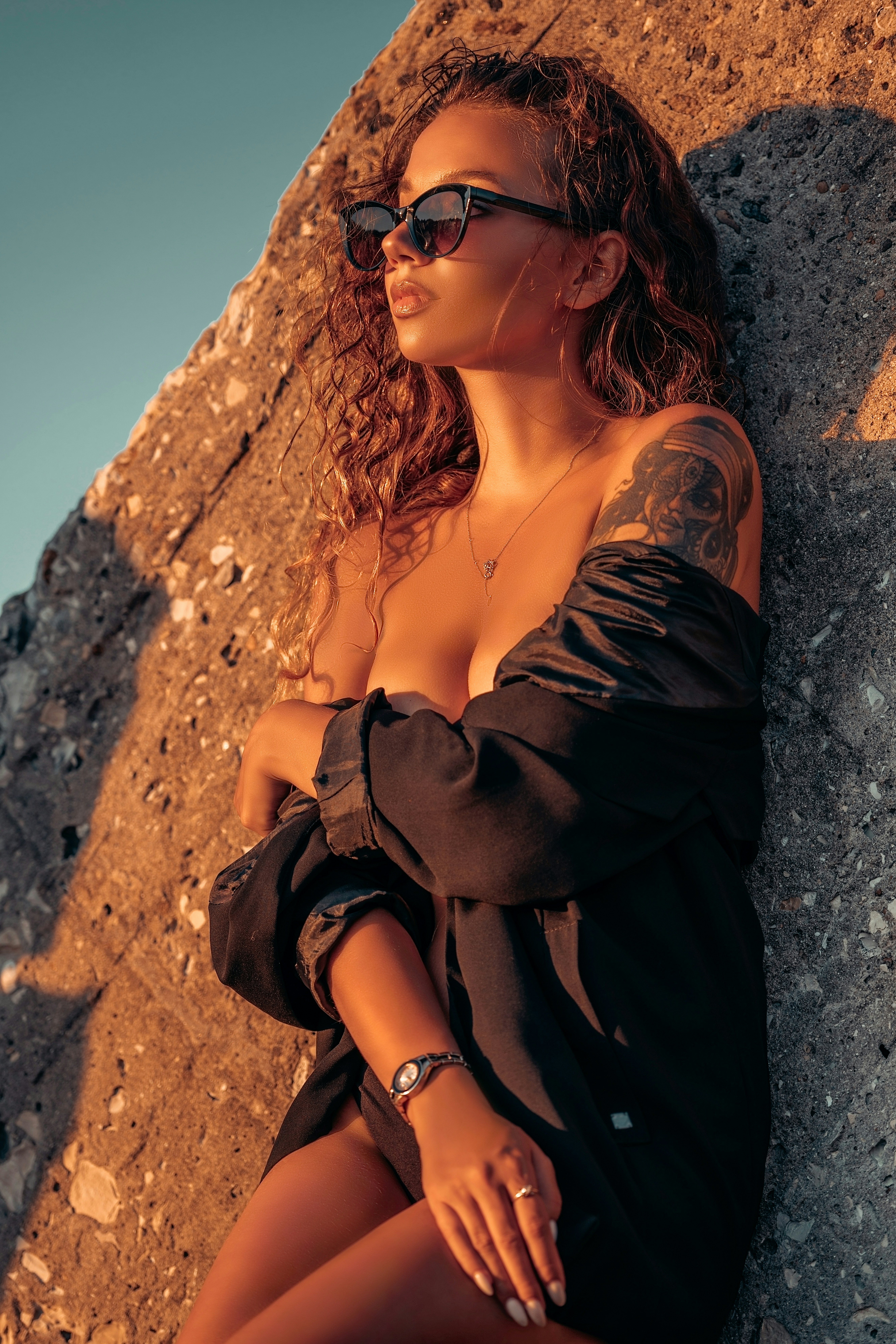 Une femme portant des lunettes de soleil assise sur un rocher