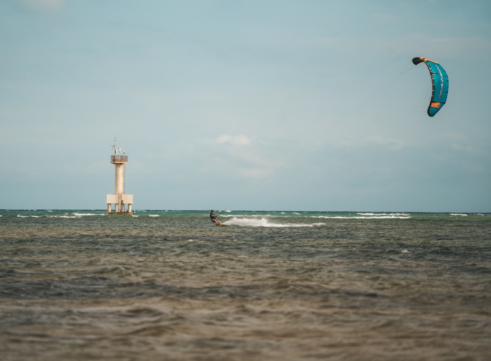 a person para sailing in the ocean next to a light house