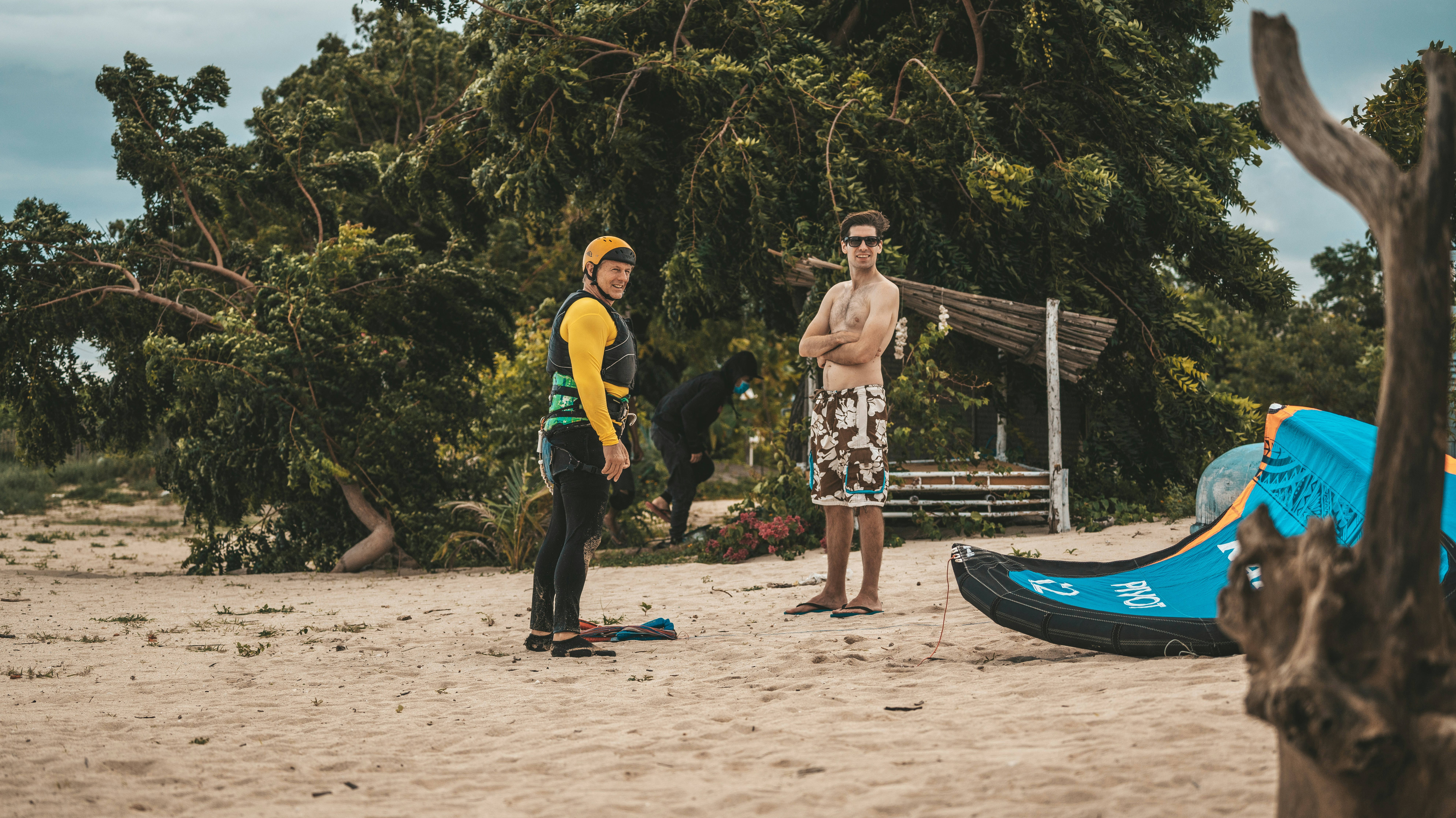 A couple of men standing on top of a sandy beach photo – Free ...