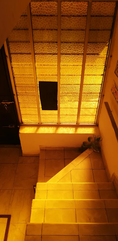 Kitchen at golden hour. Lucia stands alone at the counter where her mother used to cook. Light moves across the room.