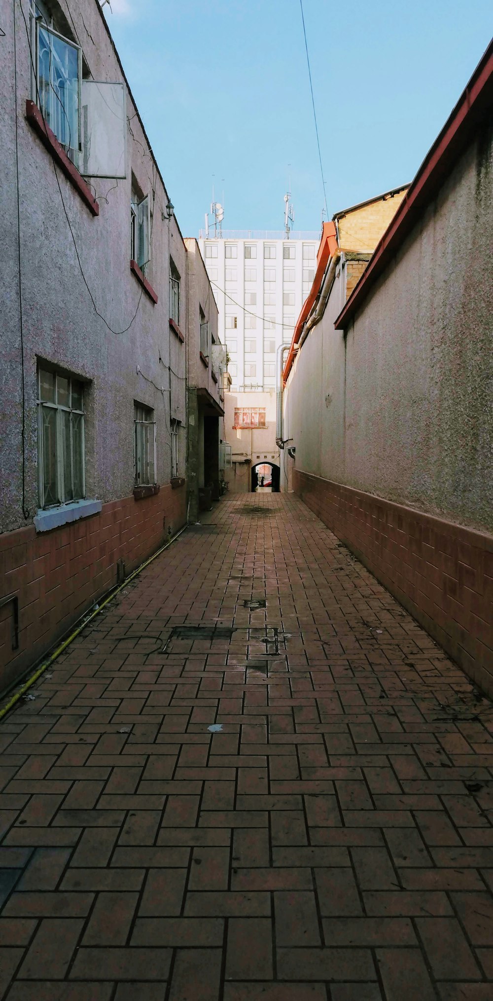 a narrow brick street with a building in the background