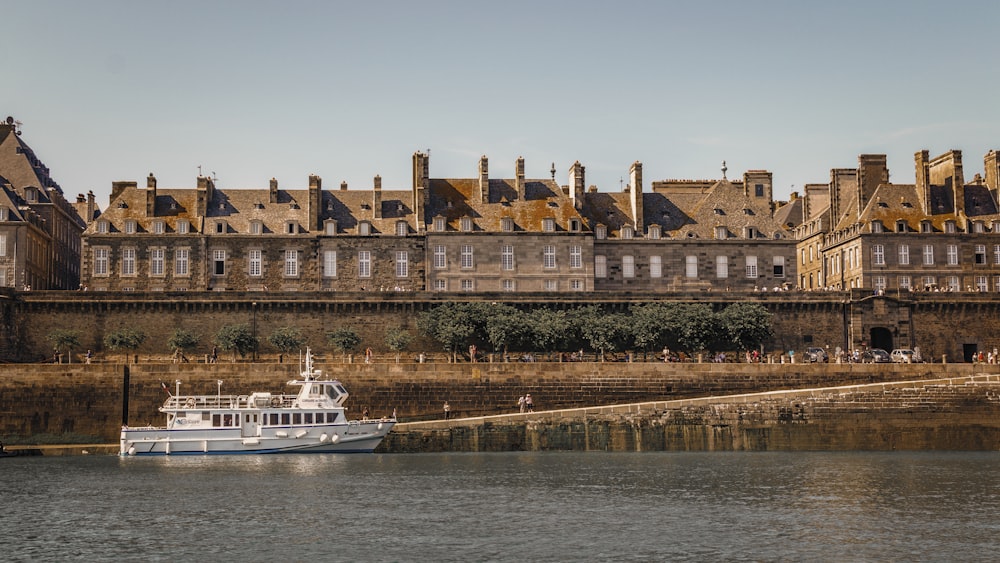 a white boat in a body of water next to a large building