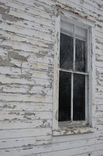 an old white house with a broken window