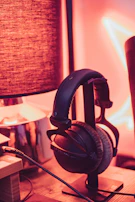 A cozy evening scene with headphones resting on a couch arm, soft lamp light glowing nearby.