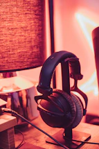 A cozy music studio corner with headphones resting on a microphone stand, softly lit by colorful ambient lights.