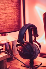 Softly glowing headphones resting beside a gently flickering candle in a dimly lit room.