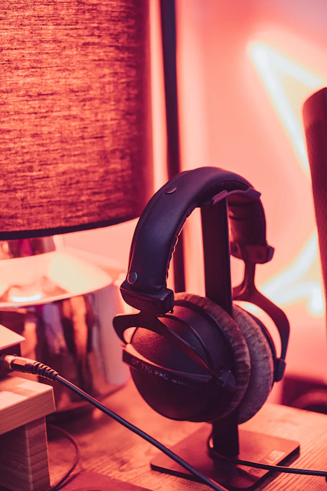 A modern wireless headset resting on a stand with subtle ambient lighting.