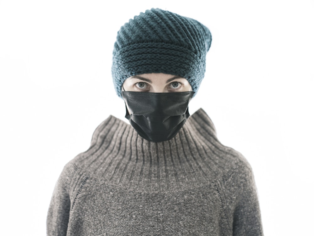 a person wearing a black mask and a knitted hat