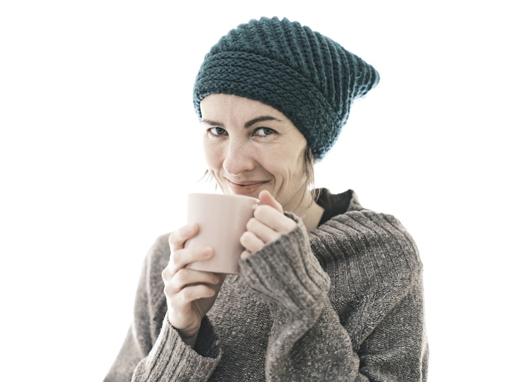 a woman wearing a knitted hat and holding a cup