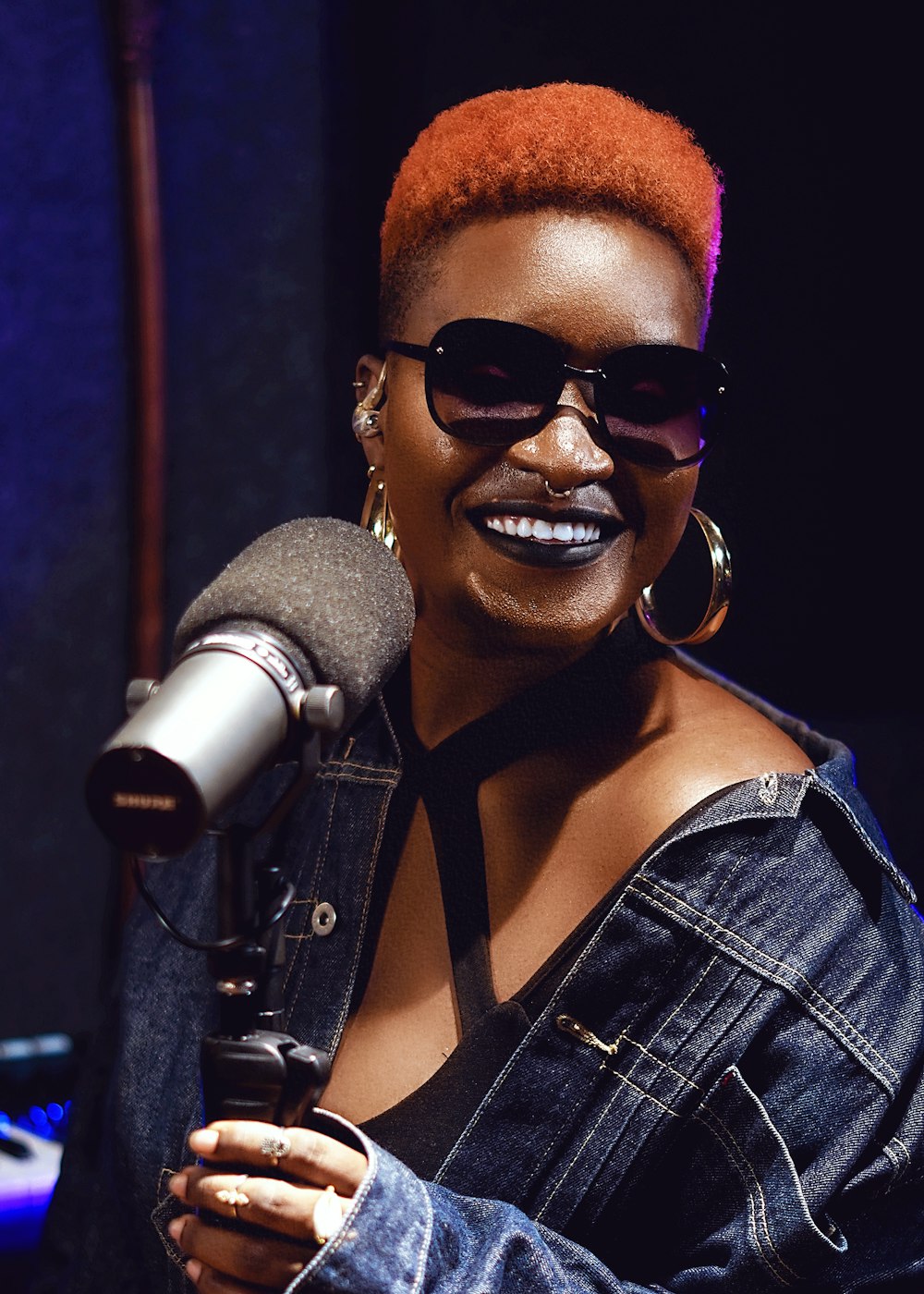 a woman with red hair and sunglasses holding a microphone