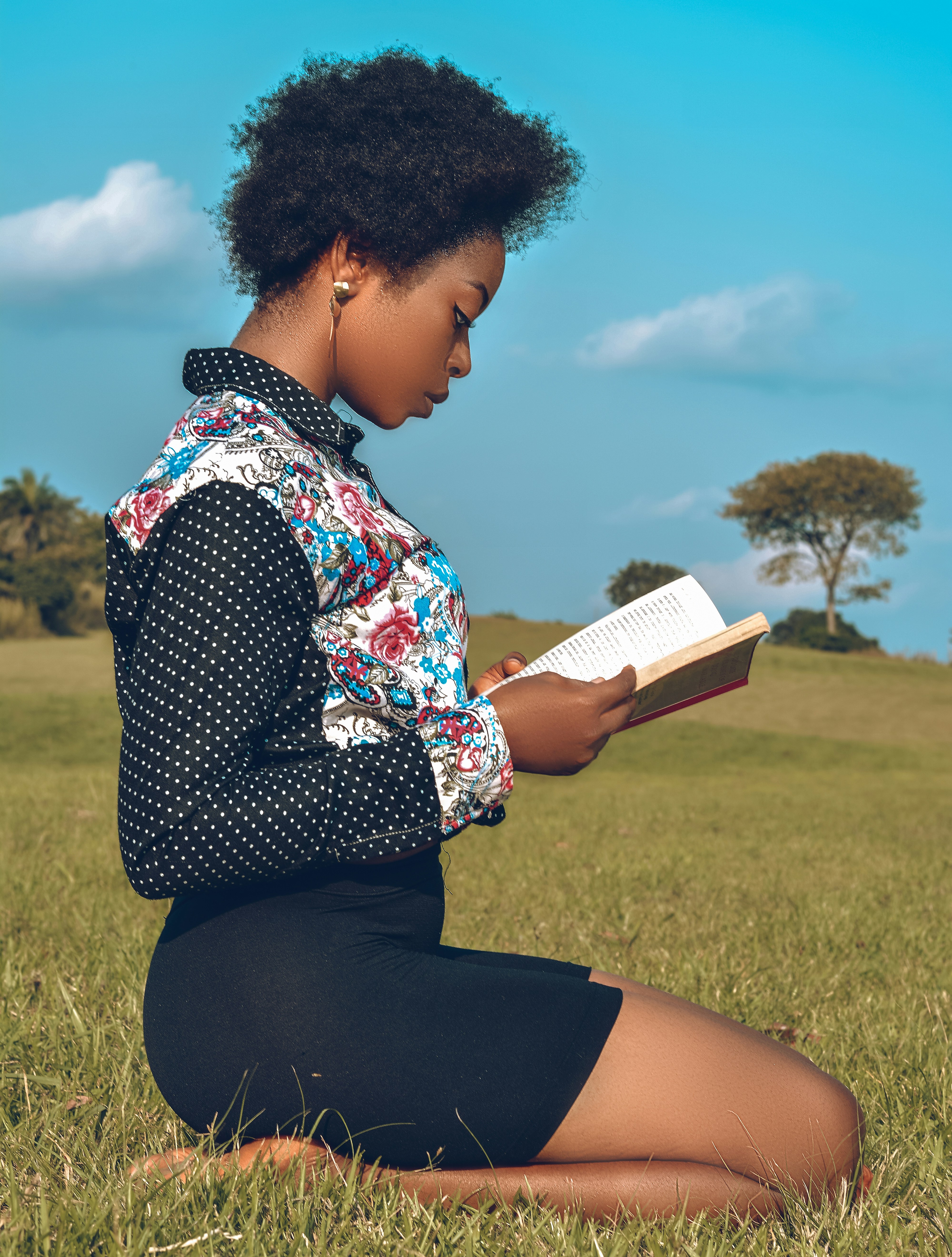 a woman sitting in the grass reading a book