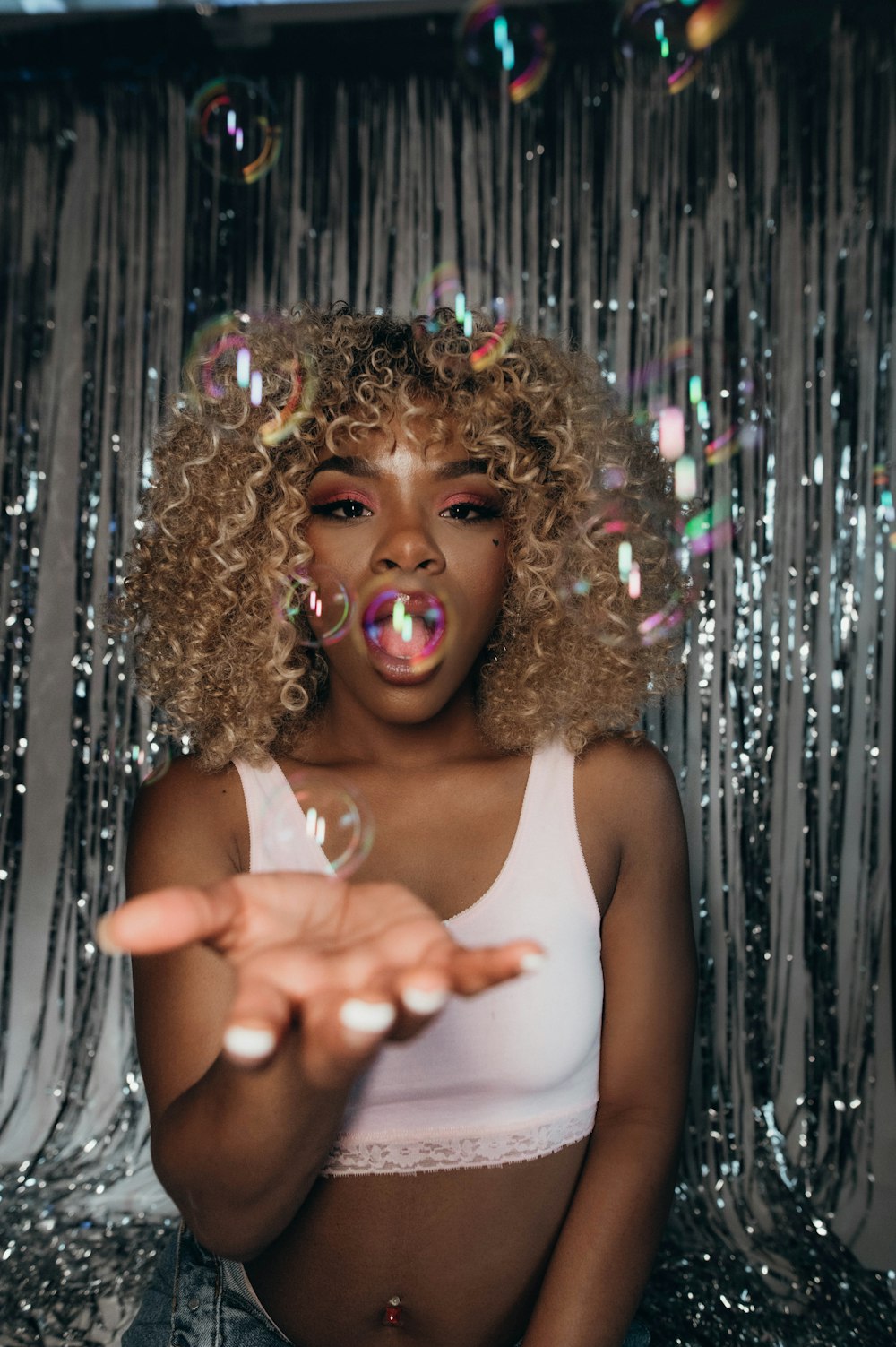 a woman blowing bubbles in front of a curtain