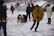 A joyful family bundled in winter gear, smiling beside their dog sleds on a snowy trail.