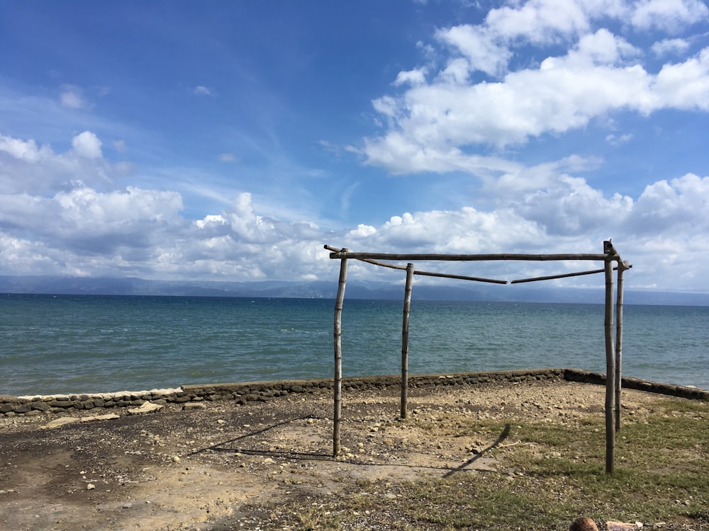 a wooden structure sitting on top of a beach next to the ocean