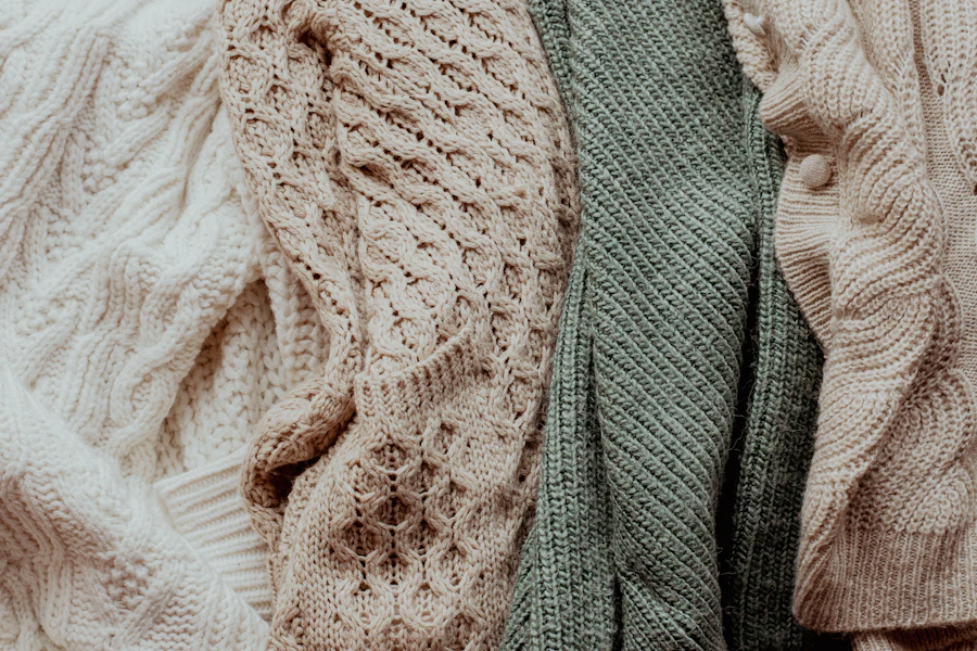 Bamboo knit jumpers hung close together in natural and sage, shot tight on the stitch