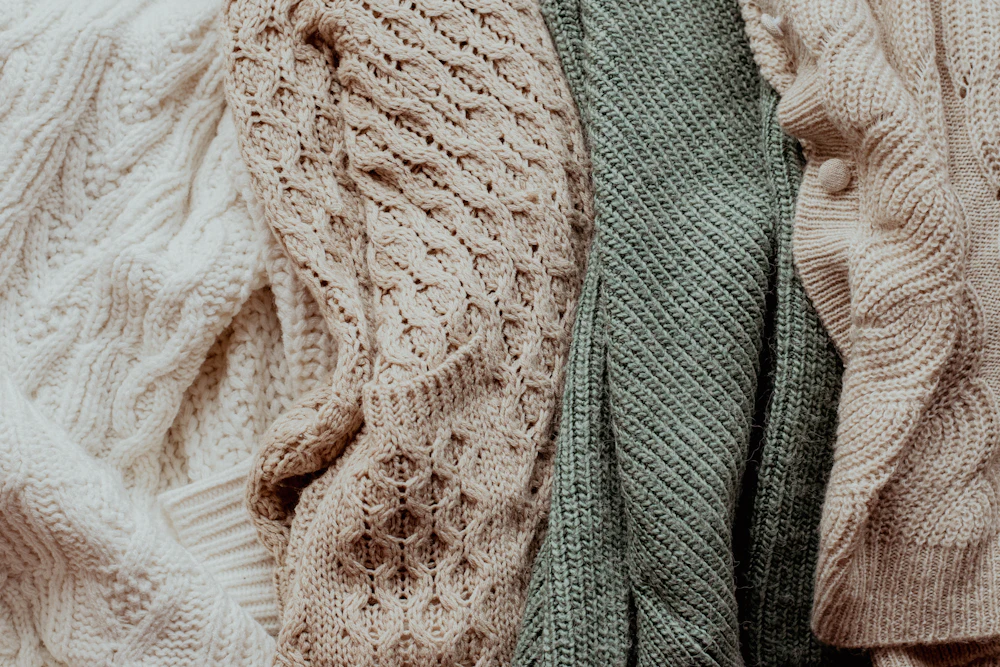 A pile of sweaters in soft colours