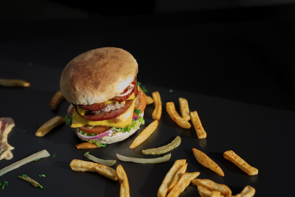 a hamburger and french fries on a black surface