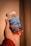 A hand holding a bottle of Simply8 Gummy Vitamins, specifically Vitamin D3 with a dosage of 2000 IU per serving. The bottle is blue with a white lid and contains 60 gummies with orange, lemon, and strawberry flavor.