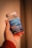 A hand holding a bottle of Simply8 Gummy Vitamins, specifically Vitamin D3 with a dosage of 2000 IU per serving. The bottle is blue with a white lid and contains 60 gummies with orange, lemon, and strawberry flavor.