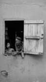 a black and white photo of a man and a child looking out of a window