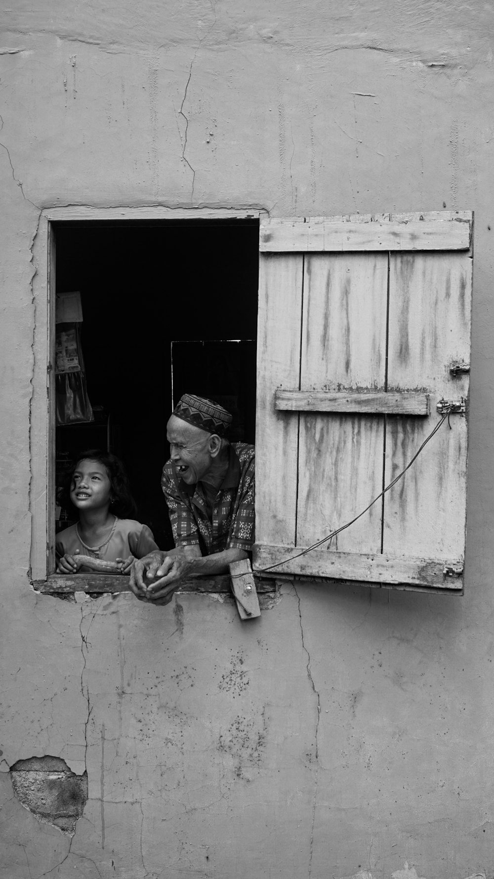 a black and white photo of a man and a child looking out of a window