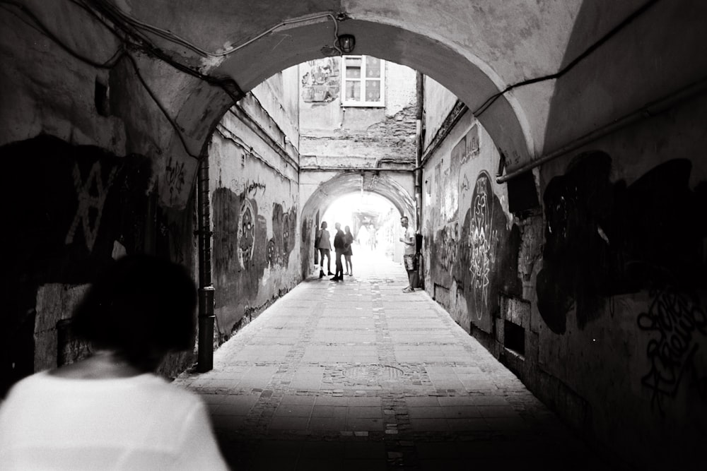 a black and white photo of people walking through a tunnel
