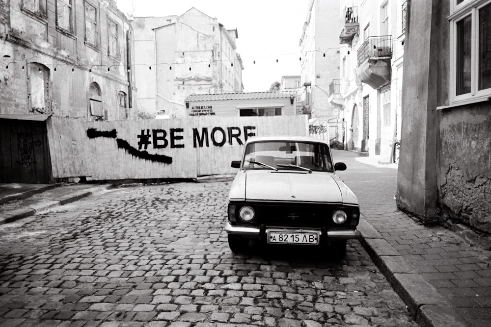 a black and white photo of a car parked on a cobblestone street