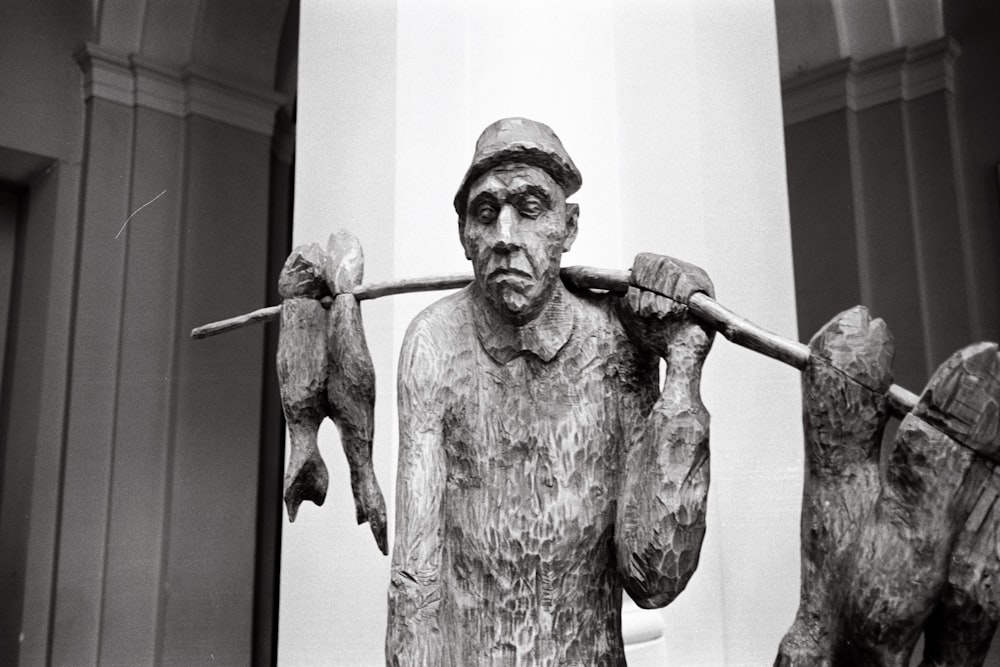 a black and white photo of a statue of a man holding a stick
