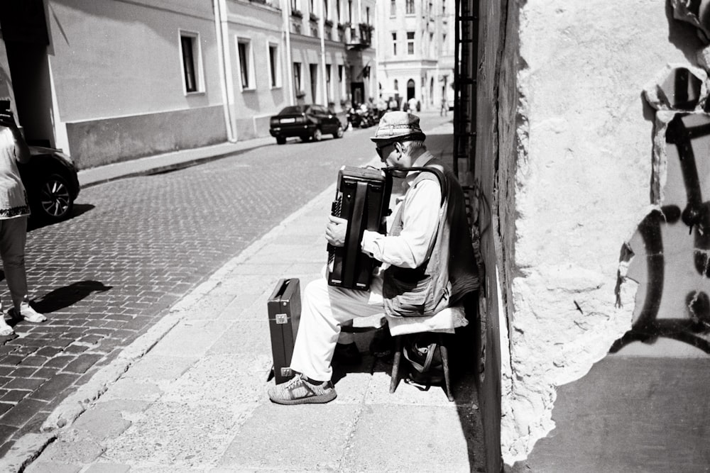 a black and white photo of a man sitting on a bench