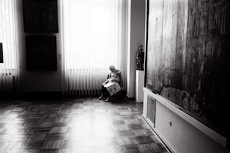 A caregiver helping an elderly person with daily activities in a bright living room.