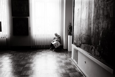 A caregiver helping an elderly person with daily activities in a bright living room.