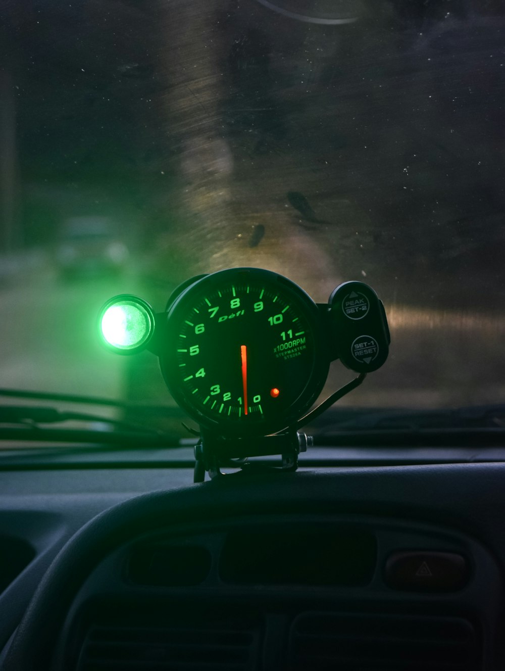 a car dashboard with a speedometer and a green light