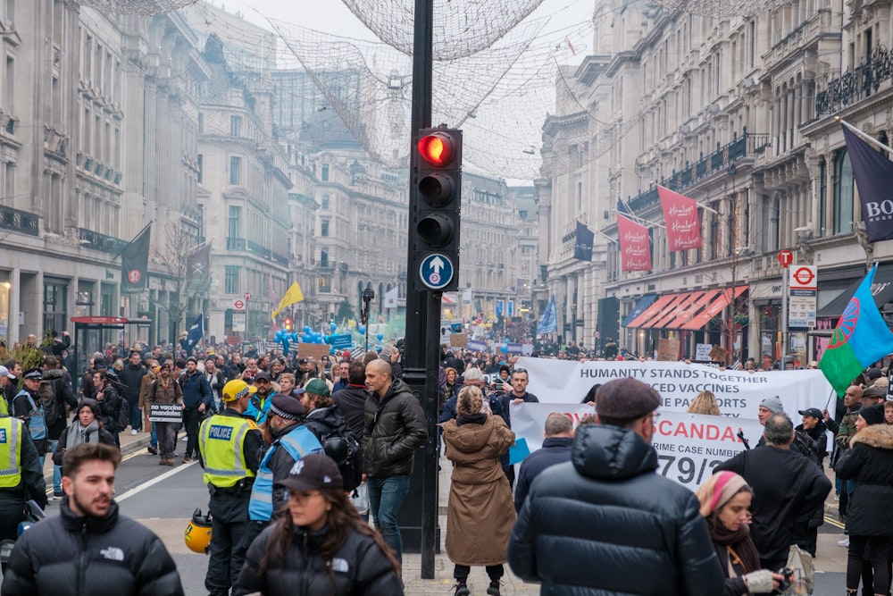 Una folla di persone che camminano lungo una strada accanto a edifici alti