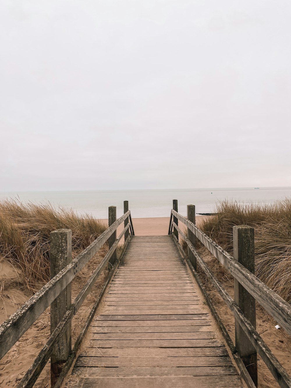 a wooden walkway leading to the beach on a cloudy day