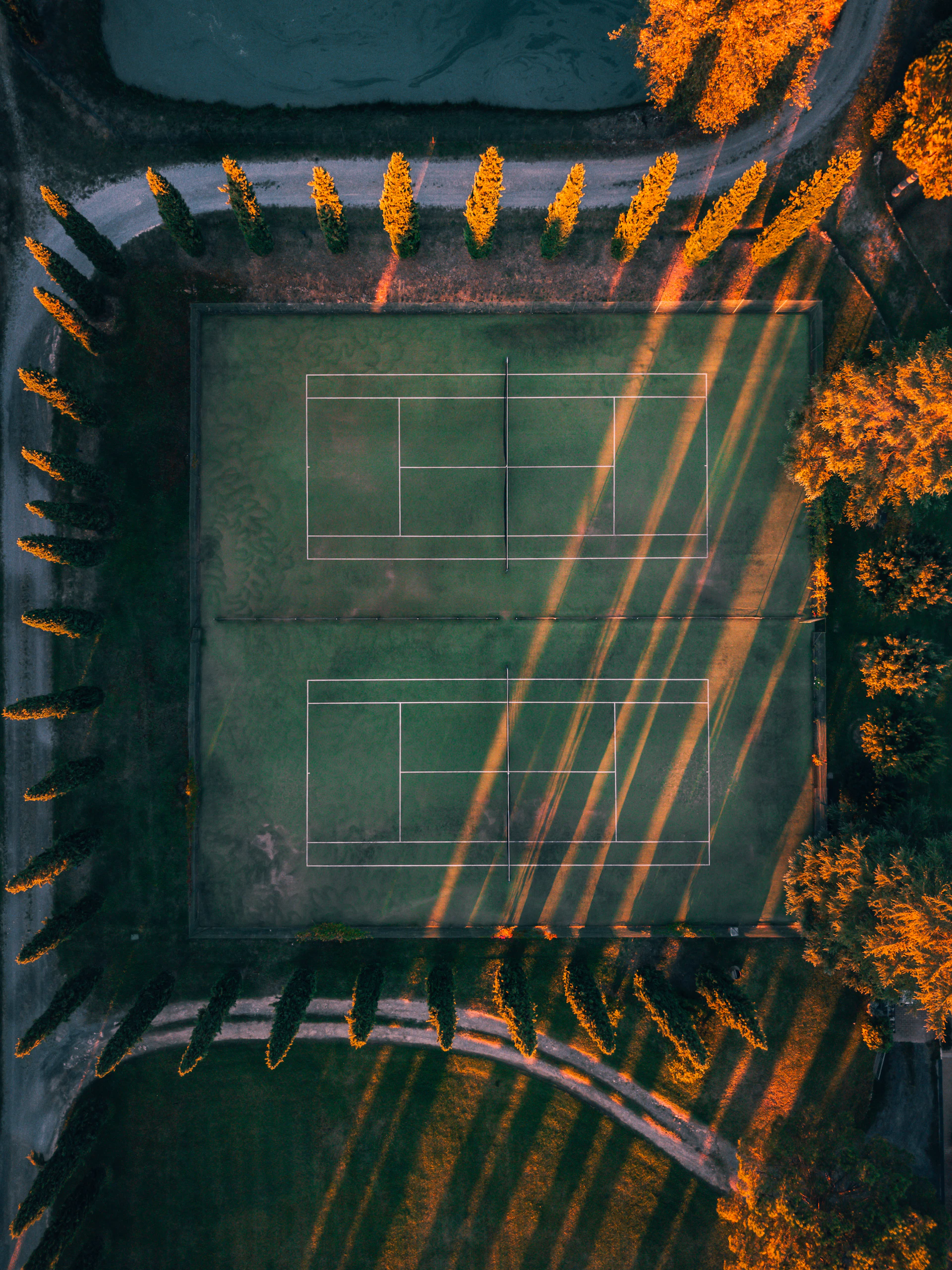 Wide angle view of raquetaviva's courts from above, capturing the lush surrounding trees and the morning mist fading as early players warm up.