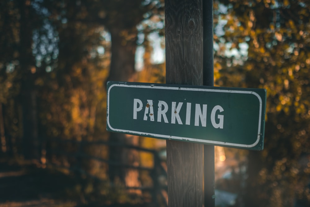 a green parking sign sitting on top of a wooden pole