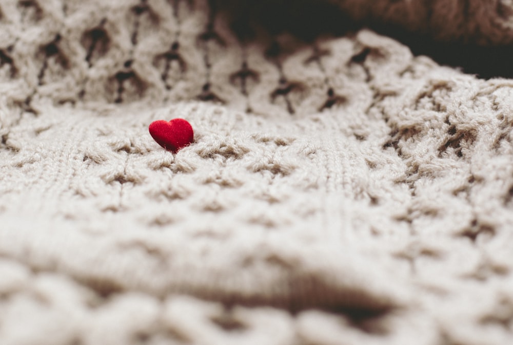 a red heart sitting on top of a white blanket