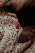 A cozy scarlet sweater draped over a chair with subtle heart motifs.
