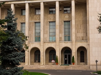 An institutional building featuring a grand entrance with stone columns and landscaping.