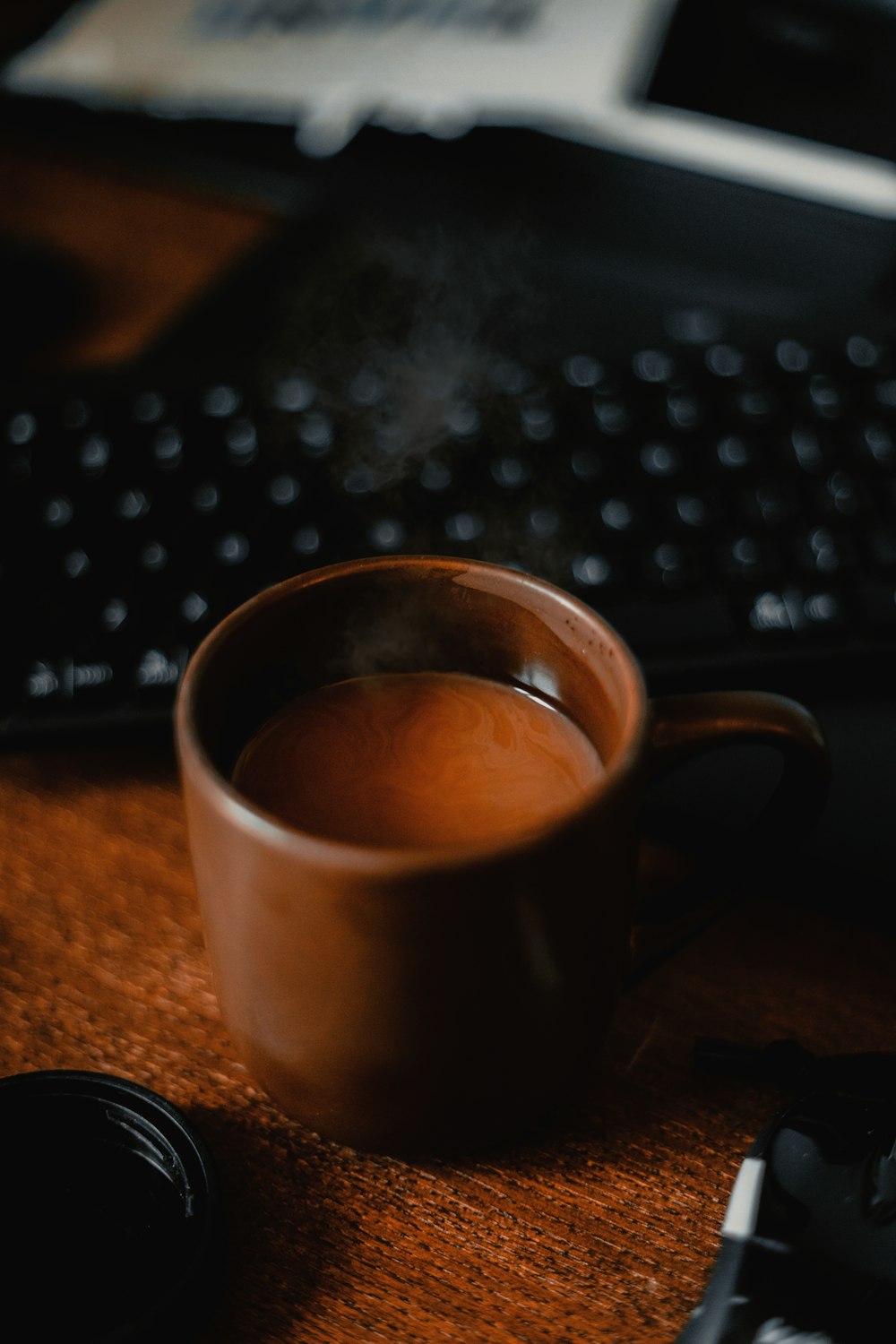 a cup of coffee sitting on a desk next to a keyboard