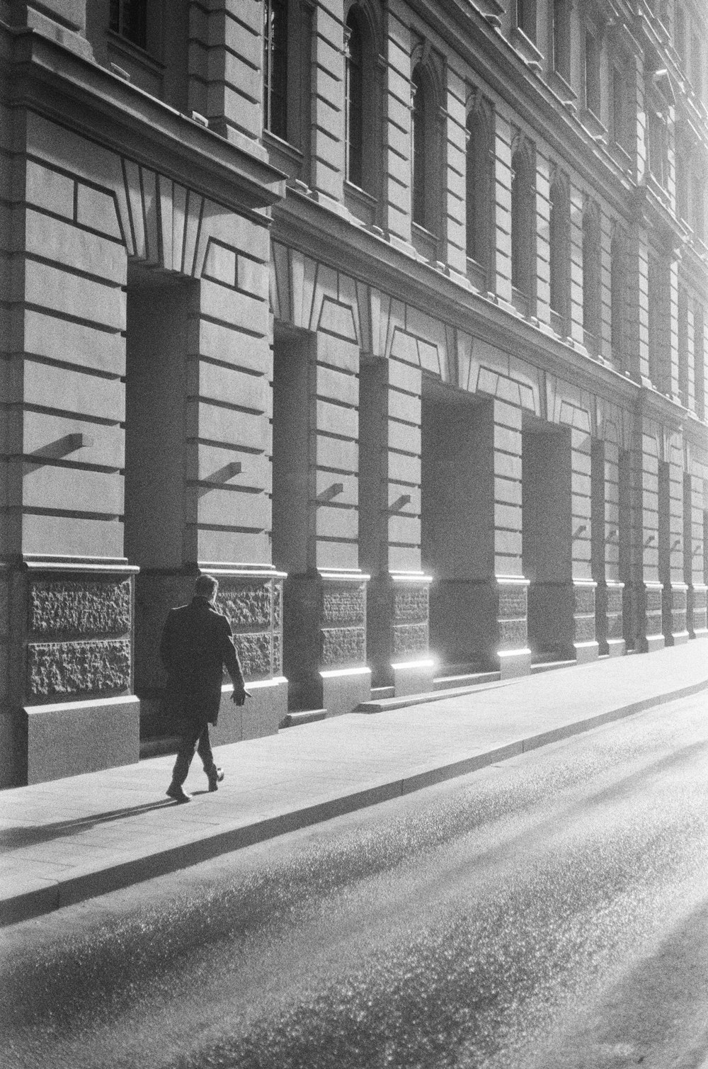 a man walking down a street next to a tall building