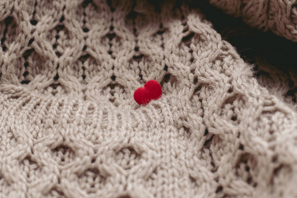 a close up of a sweater with a red heart on it