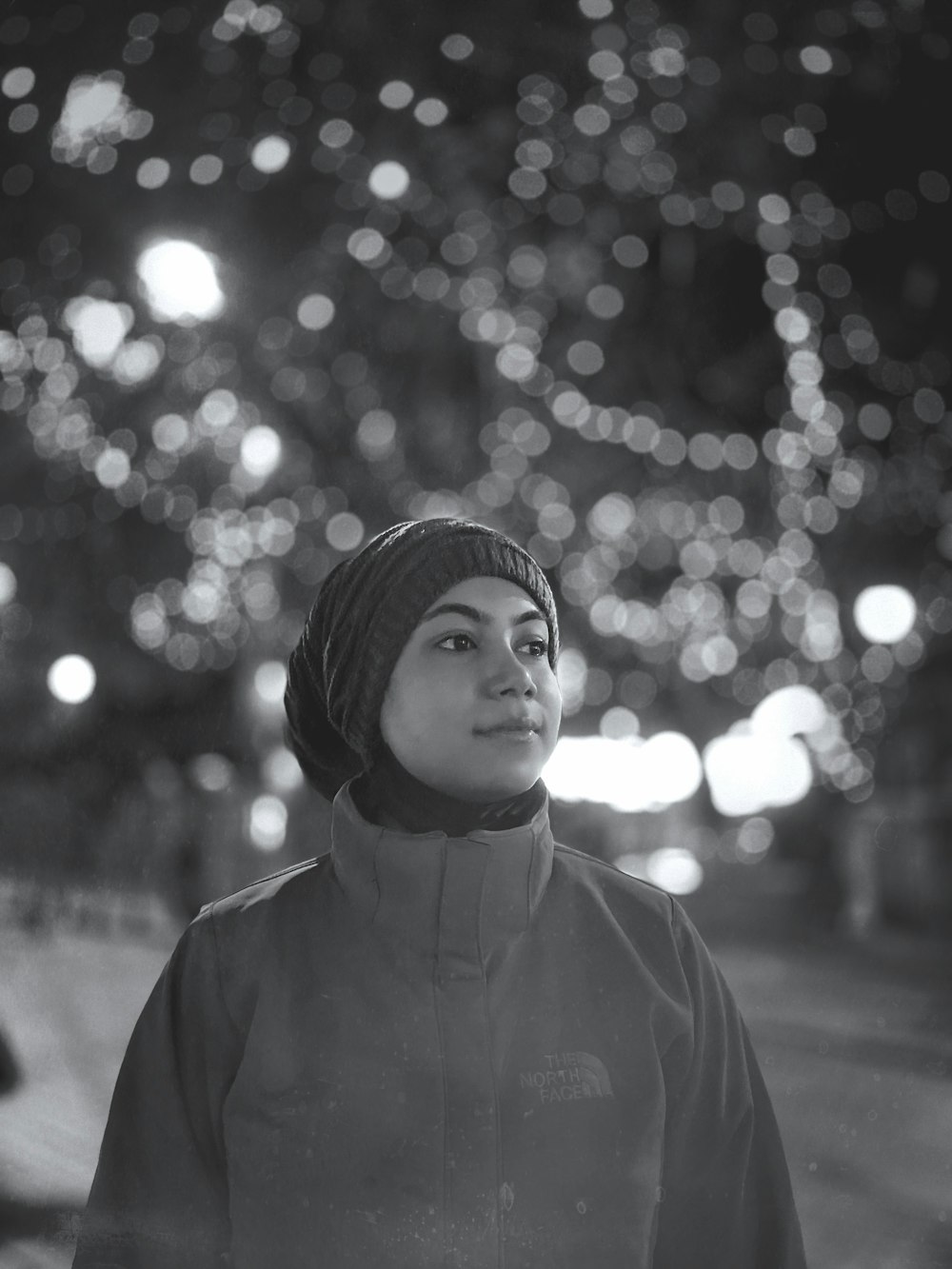 a woman standing in front of a street filled with lights