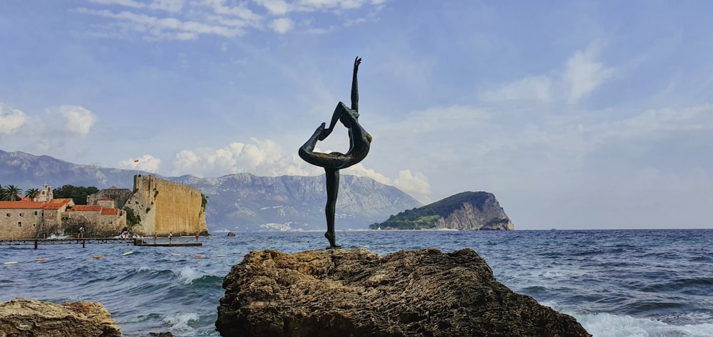 a person doing a yoga pose on a rock near the ocean