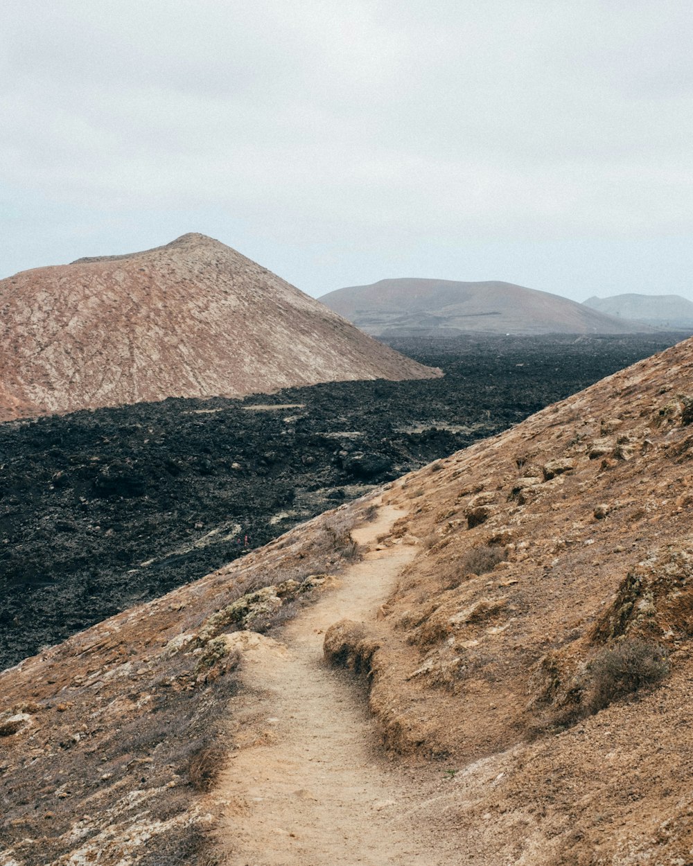 a dirt path with a mountain in the background