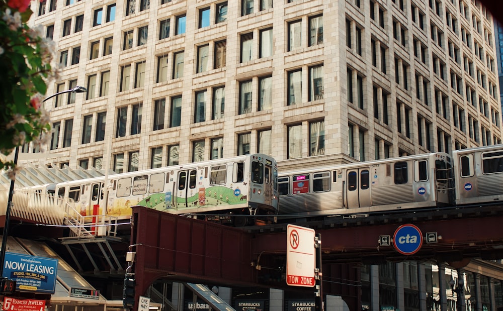 a train traveling over a bridge in front of a tall building