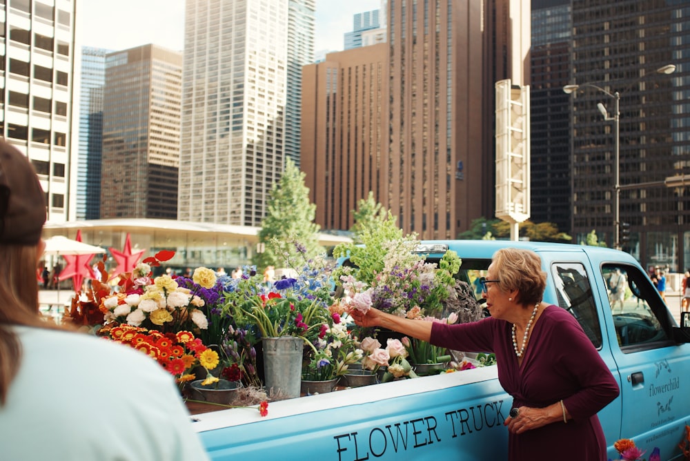 a woman pointing at a flower truck in a city